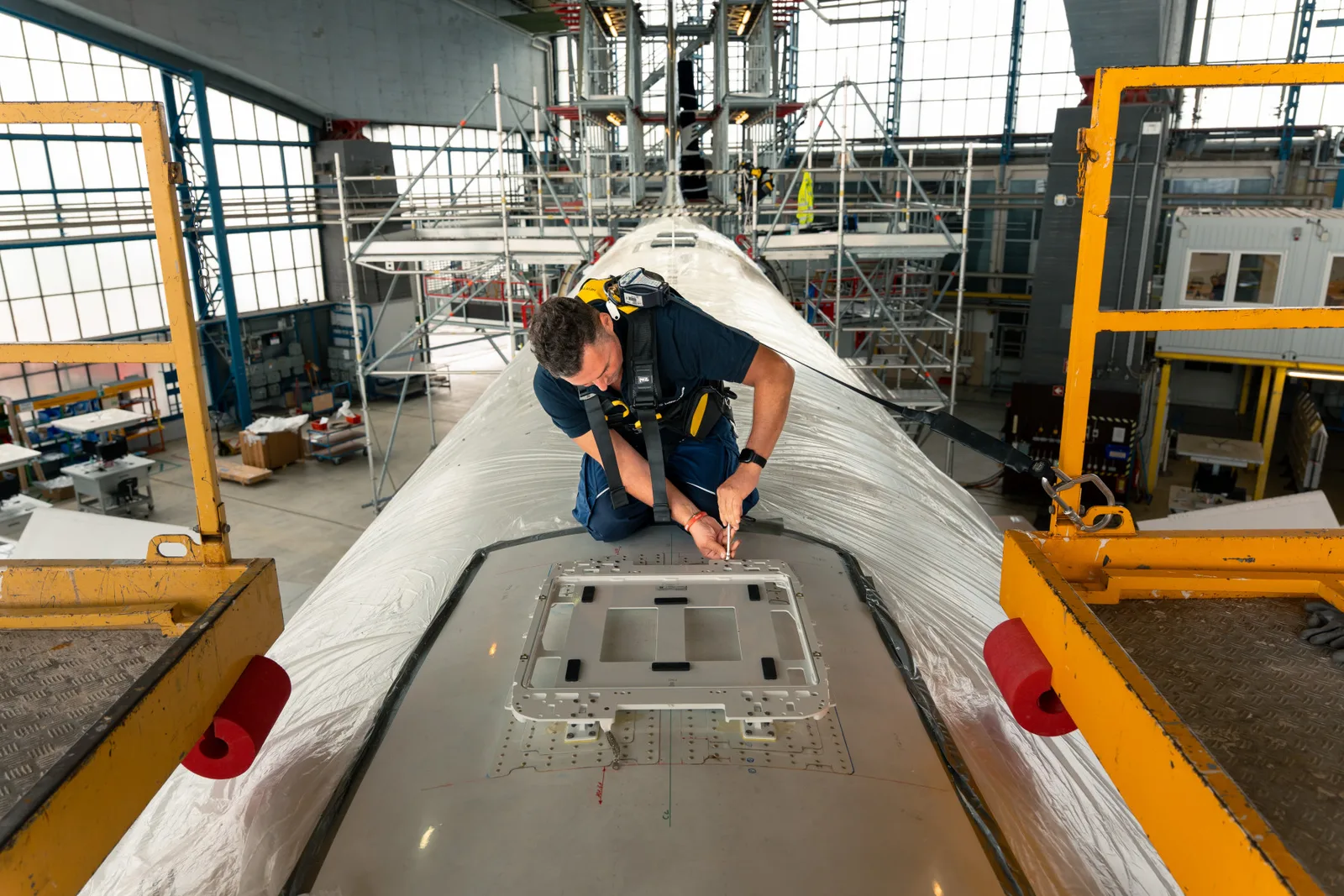 Techniker montiert die flache Starlink-Antenne auf dem Rumpf eines Lufthansa-Flugzeugs im Hangar