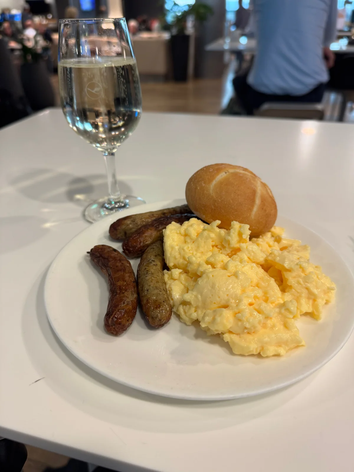 Frühstück in der Flughafen-Lounge: Rührei, Würstchen und ein Glas Sekt